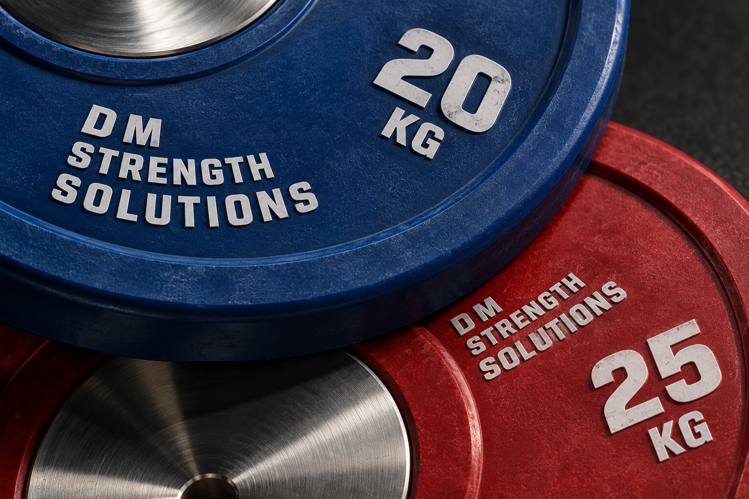 Close-up of overlapping blue 20 kg and red 25 kg plates with DM Strength Solutions printed on both.